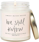 Sweet Water Decor Be Still and Know scented soy wax candle with sea salt, jasmine, wood, and cream fragrance in a 9oz clear jar with gold lid and 40-hour burn time